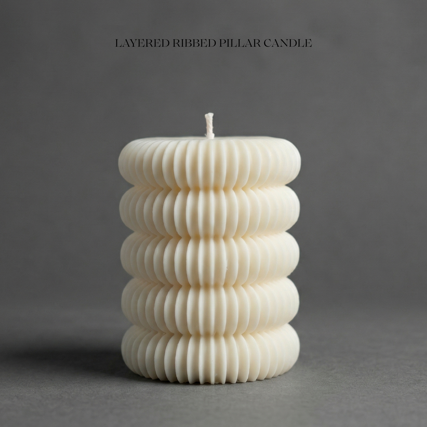 White ribbed pillar candle on a gray background