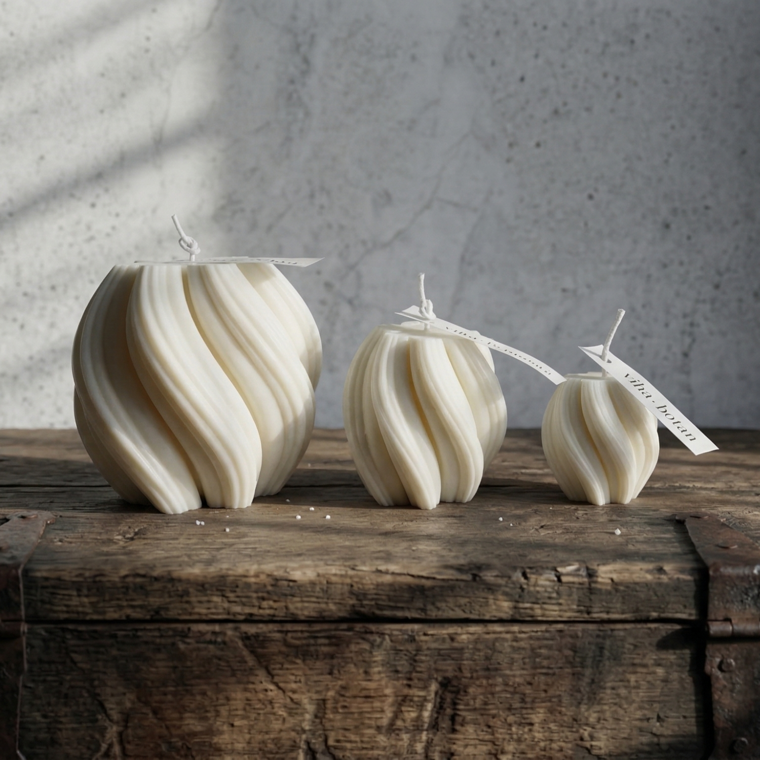 Three decorative candles on a wooden surface with a gray textured background