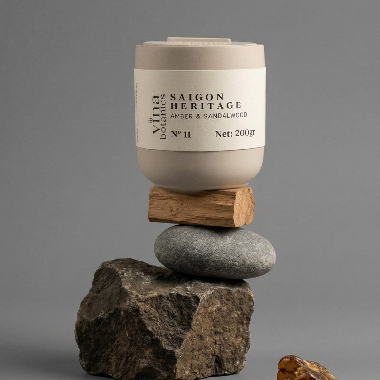 Candle labeled 'Saigon Heritage' on a stack of stones with a gray background