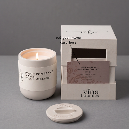 White candle in a container with a branded box and card on a gray background