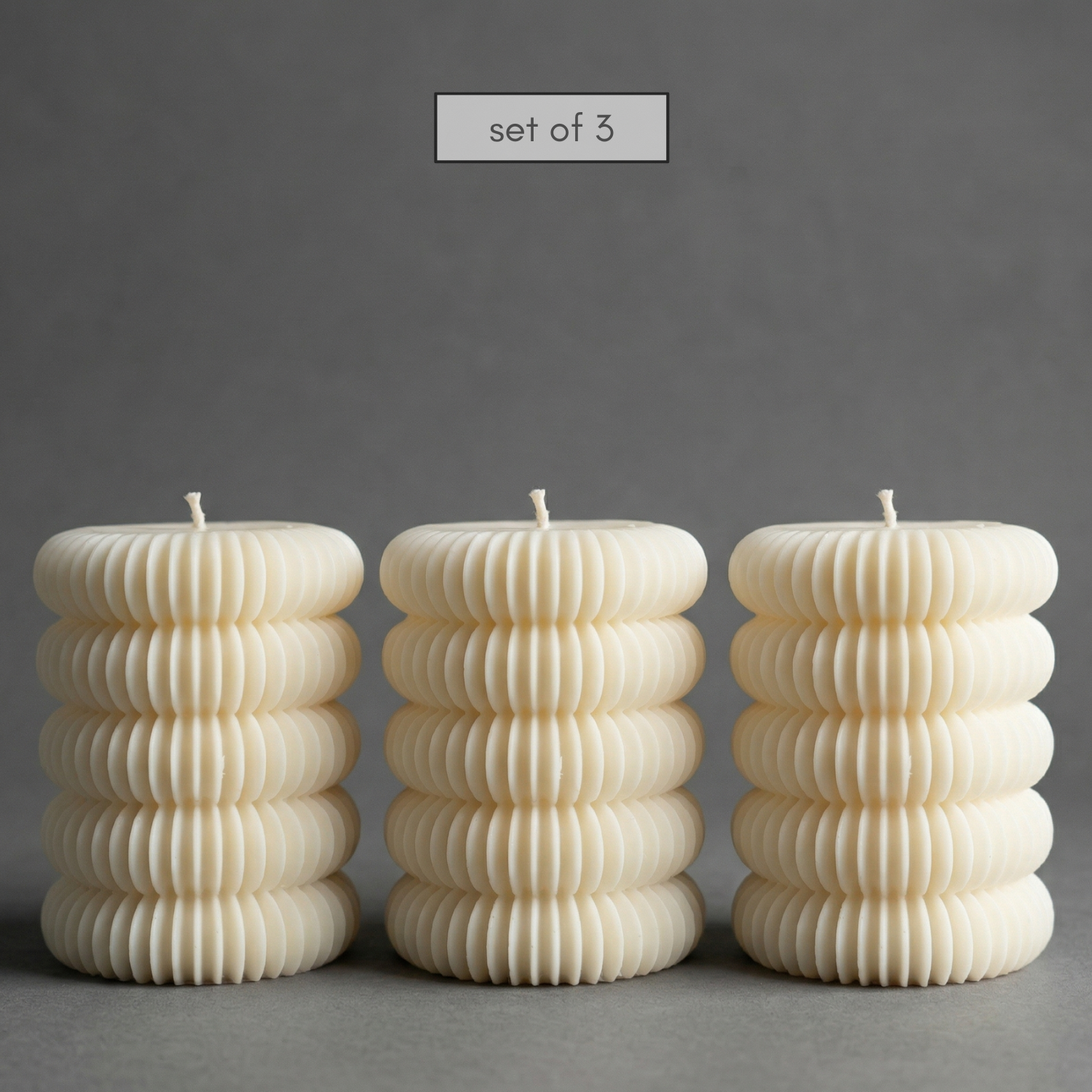 Set of three ribbed candles on a gray background