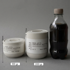 Two containers labeled 'Holan's Ancient Santal' with measurements and a bottle of dark liquid on a gray background.