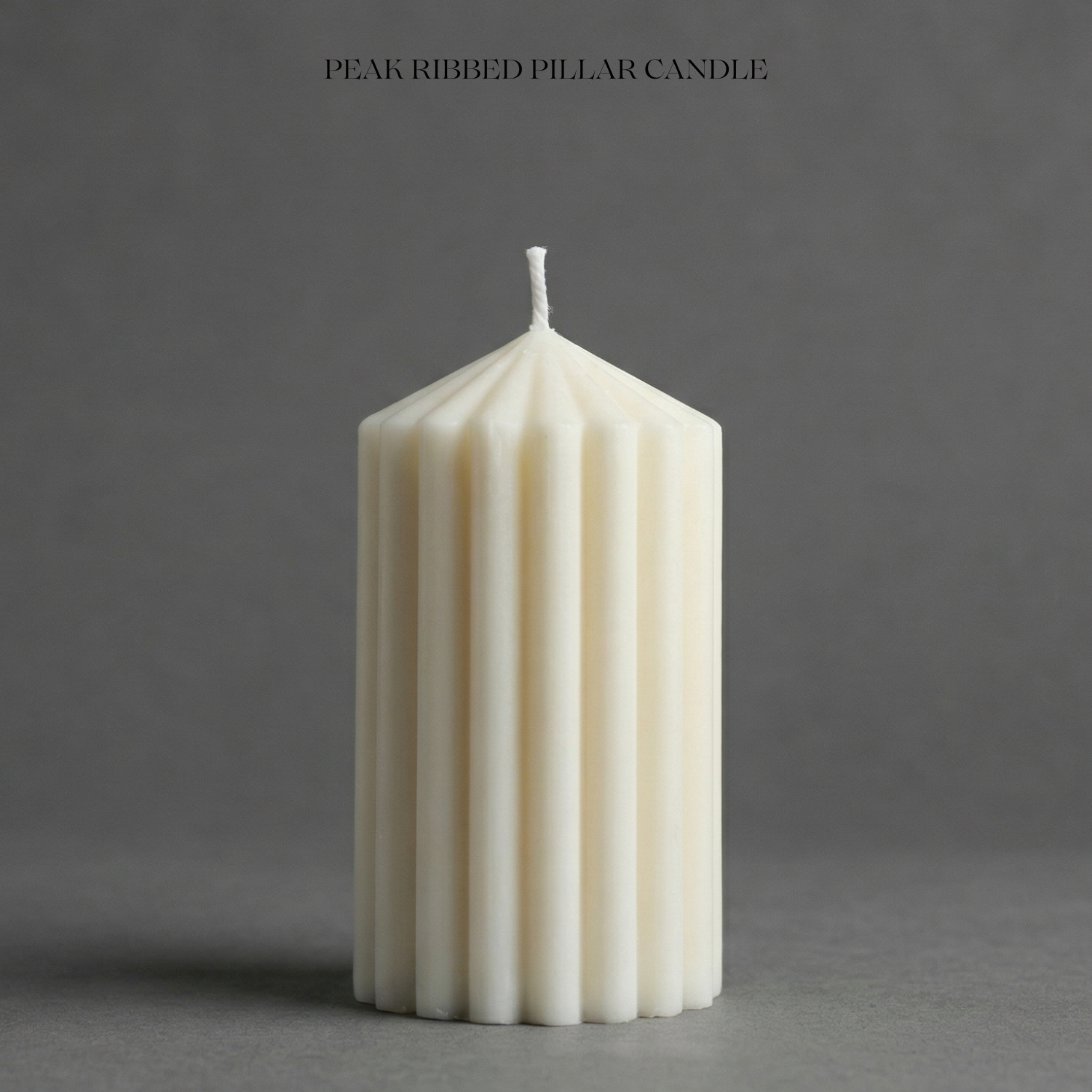 White ribbed pillar candle on a gray background